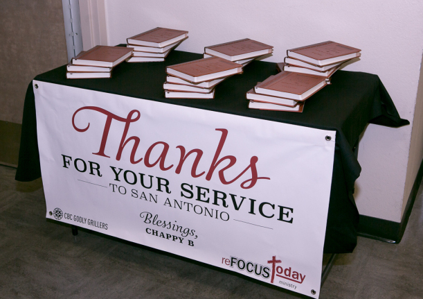 table with 6 stacks of books, 3 books in each stack. Signage in from of table reads "THANKS FOR YOUR SERVICE - TO SAN ANTONIO